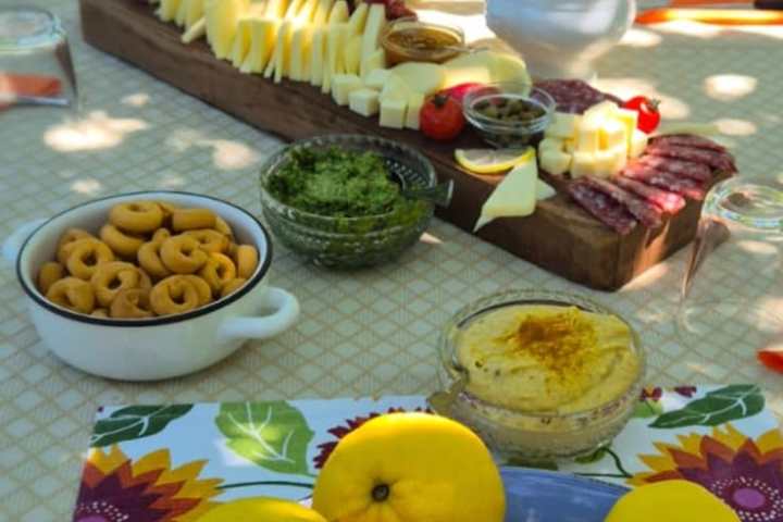 Outdoor table with lemons, cheese, fruits, and snacks arranged elegantly.