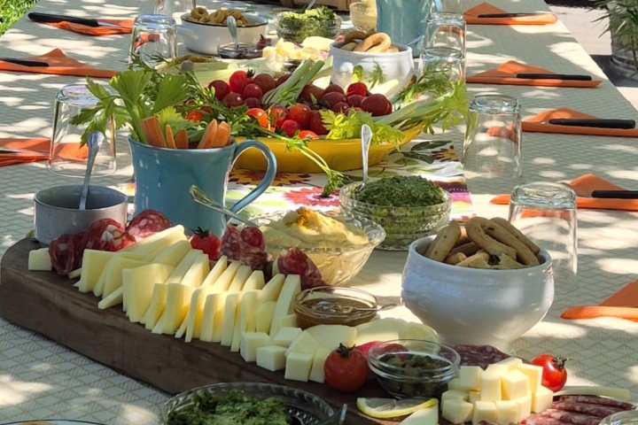 Outdoor table with charcuterie boards, cheeses, fruits, and breads.