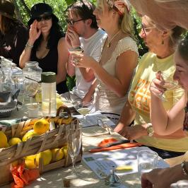 Group of people sitting at a table with lemons and drinks outdoors.