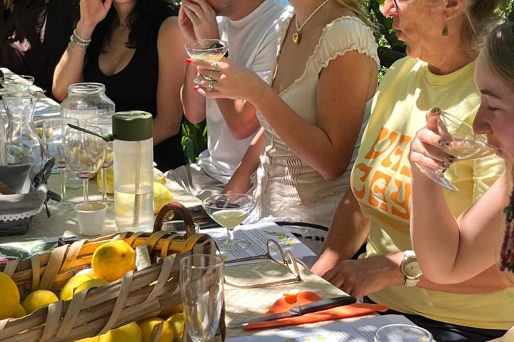 Group of people sitting at a table with lemons and drinks outdoors.