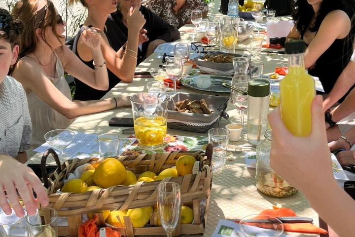 Group of people dining outdoors at a table with lemons and drinks.