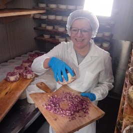 a person sitting on top of a wooden cutting board with a cake