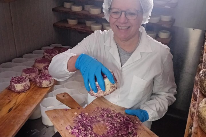 a person sitting on top of a wooden cutting board with a cake