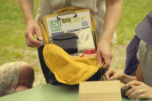 Person showing yellow backpack with papers and items inside on an outdoor table.
