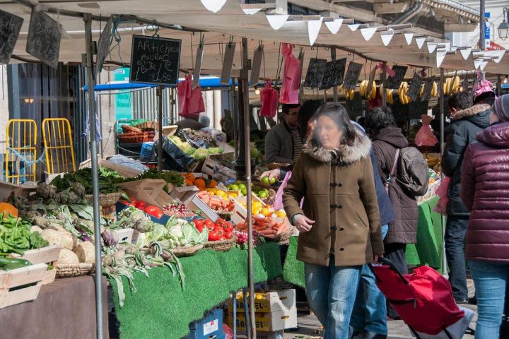Busy outdoor market with fresh produce and shoppers.