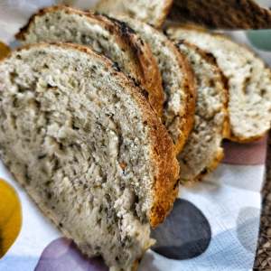 Sliced bread with herbs on a colorful napkin in a basket.