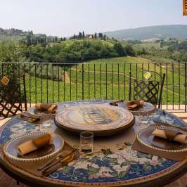 Round table set on balcony overlooking vineyards and hills.