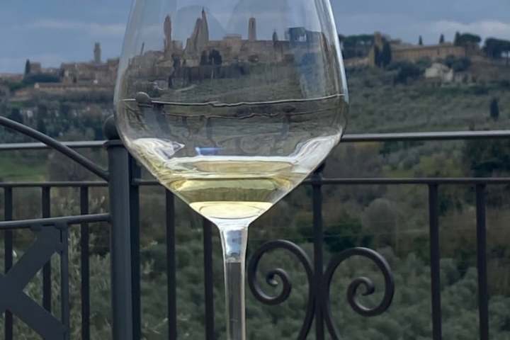 Glass of white wine on a table with scenic landscape in background.