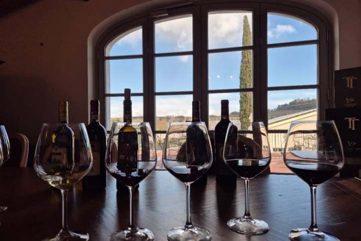 Wine glasses and bottles on a table with a window view of a landscape.