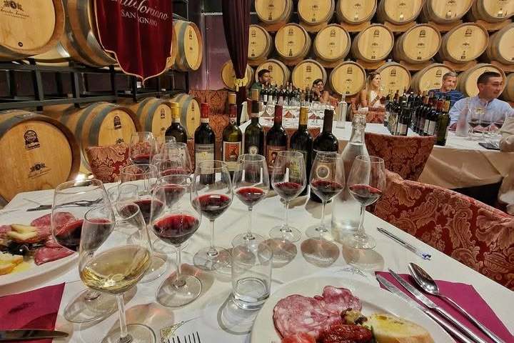 Wine tasting setup with barrels, glasses, and charcuterie on a table.