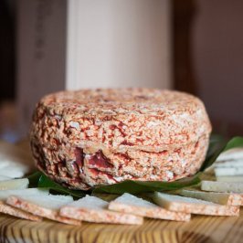 Round cheese wheel with sliced pieces on a wooden platter.