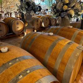 Wooden barrels and flower arrangements in a rustic winery setting.