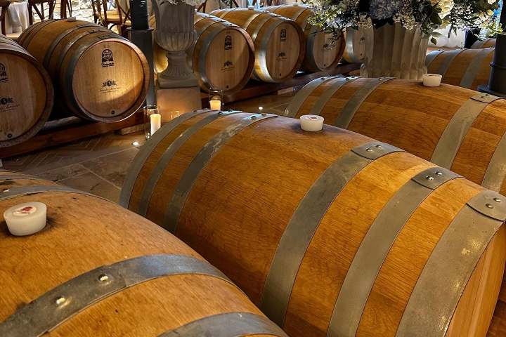 Wooden barrels and flower arrangements in a rustic winery setting.