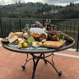 Food and wine on a table with a scenic hill town view.
