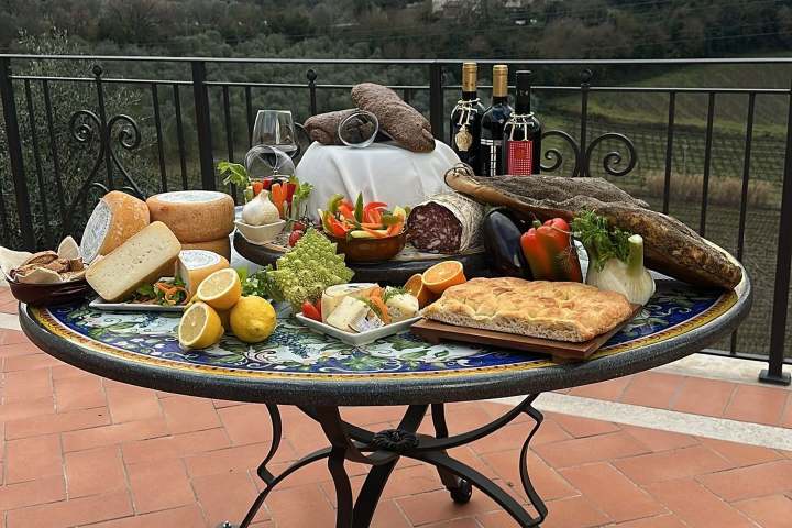 Food and wine on a table with a scenic hill town view.