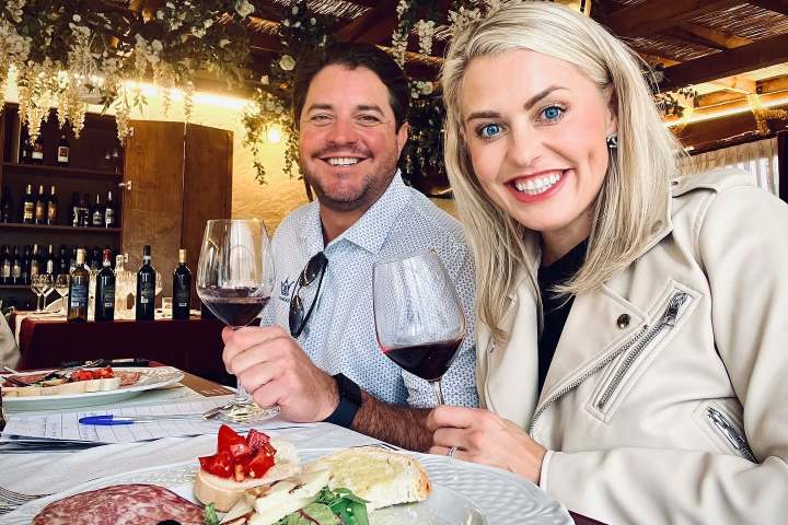 Two people smiling with wine glasses at a table with charcuterie.
