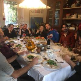 Group enjoying lunch with wine around a farmhouse table in Tuscany