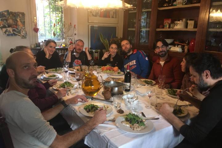 Group enjoying lunch with wine around a farmhouse table in Tuscany