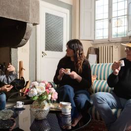 Guests relaxing with coffee by the fireplace in a Tuscan villa sitting room