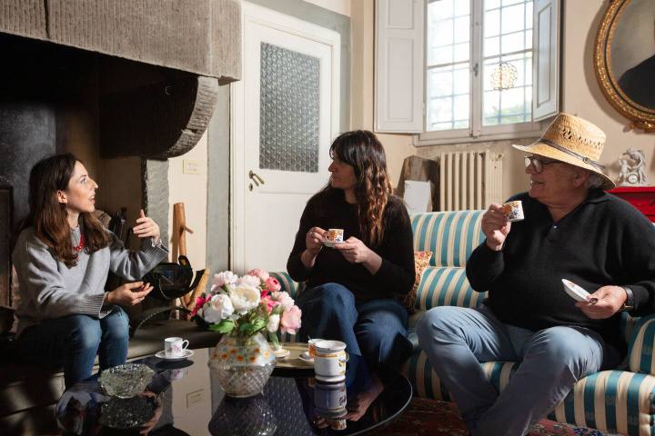 Guests relaxing with coffee by the fireplace in a Tuscan villa sitting room