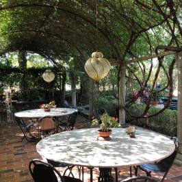 Shaded pergola terrace with tables in a Tuscan villa garden