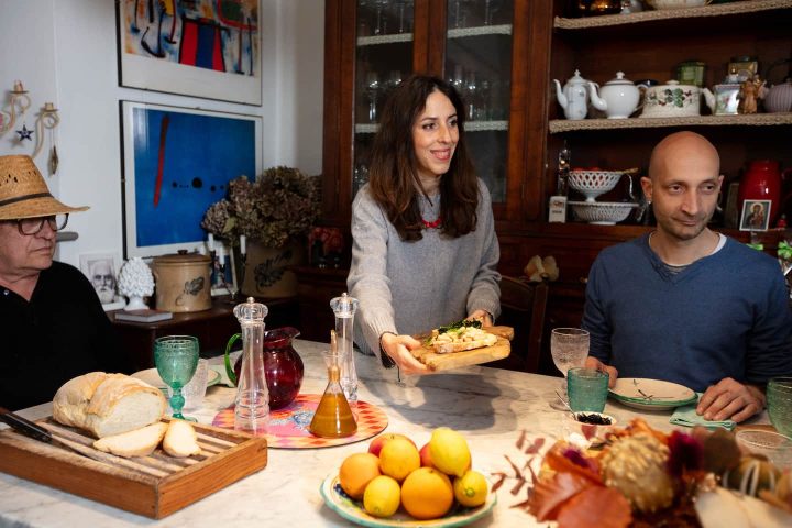 Guests at a farmhouse table with bread, oranges and olive oil in Chianti